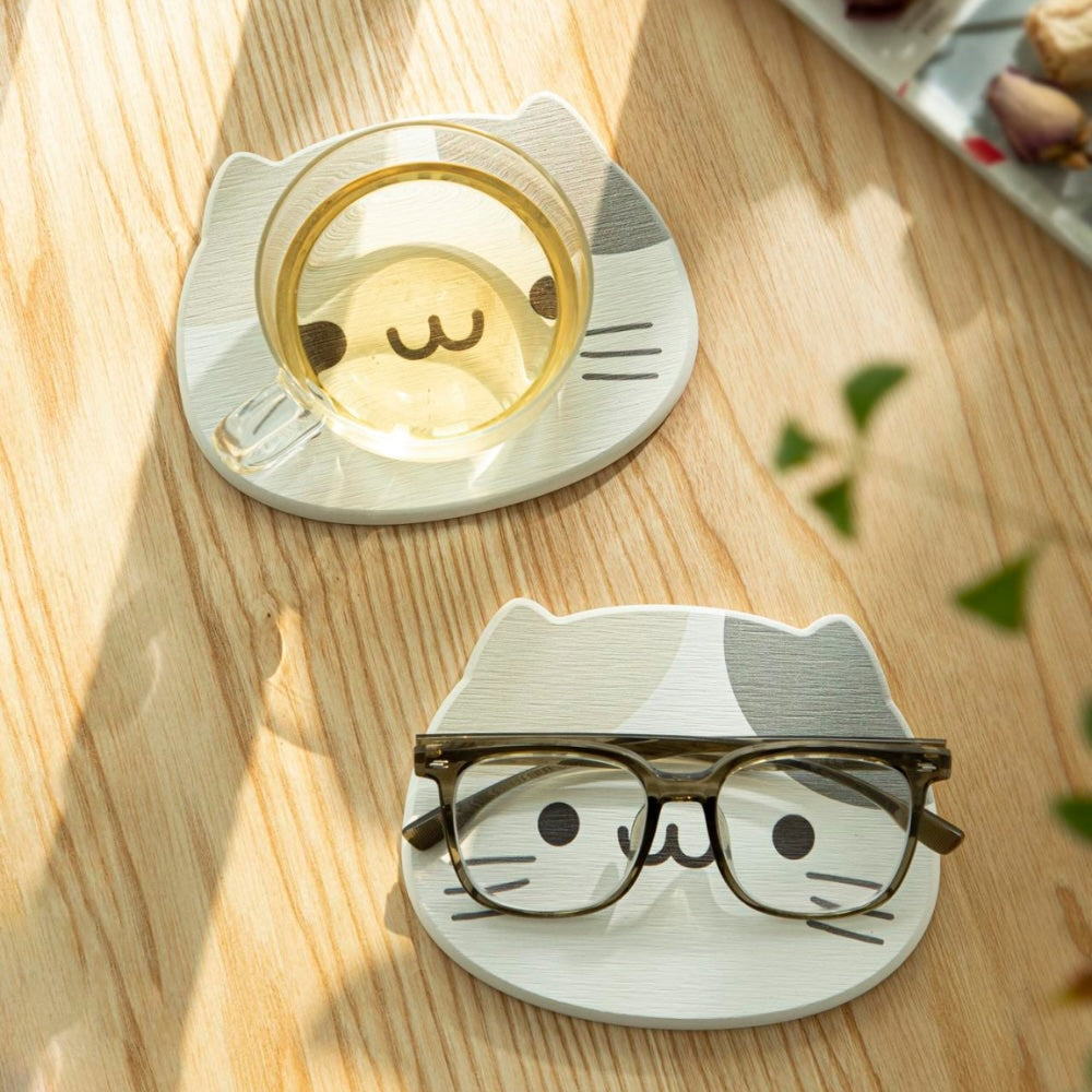 Large diatomaceous earth coaster with cat print on a wooden table with a glass of tea and spectacles