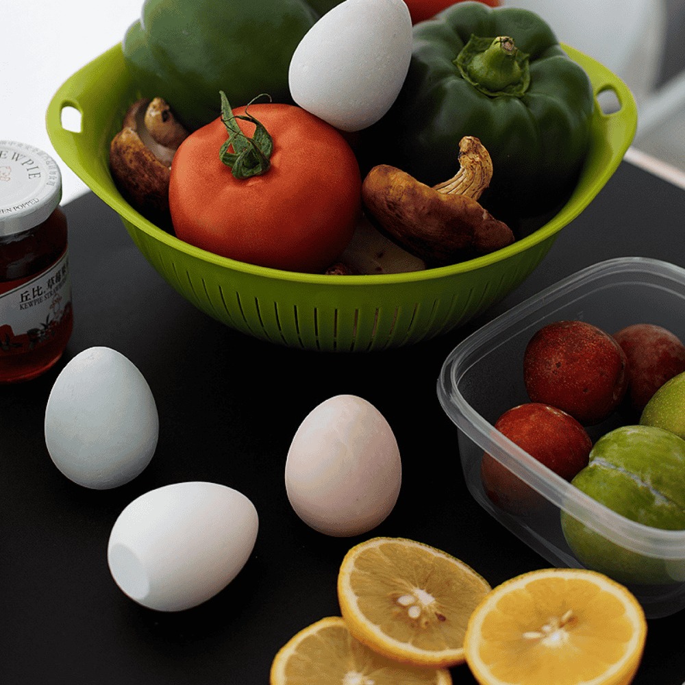 Green colander with vegetables and diatomite drying eggs on a dark table