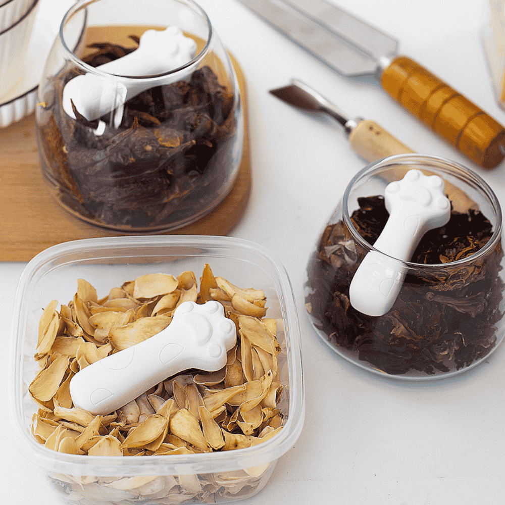 Three containers filled with herbs and spices and paw-shaped diatomite drying blocks 