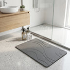 Gray diatomite bath mat on a bathroom floor with a modern design, featuring a wooden vanity and shower area.