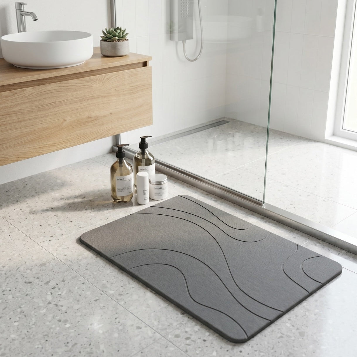 Gray diatomite bath mat on a bathroom floor with a modern design, featuring a wooden vanity and shower area.