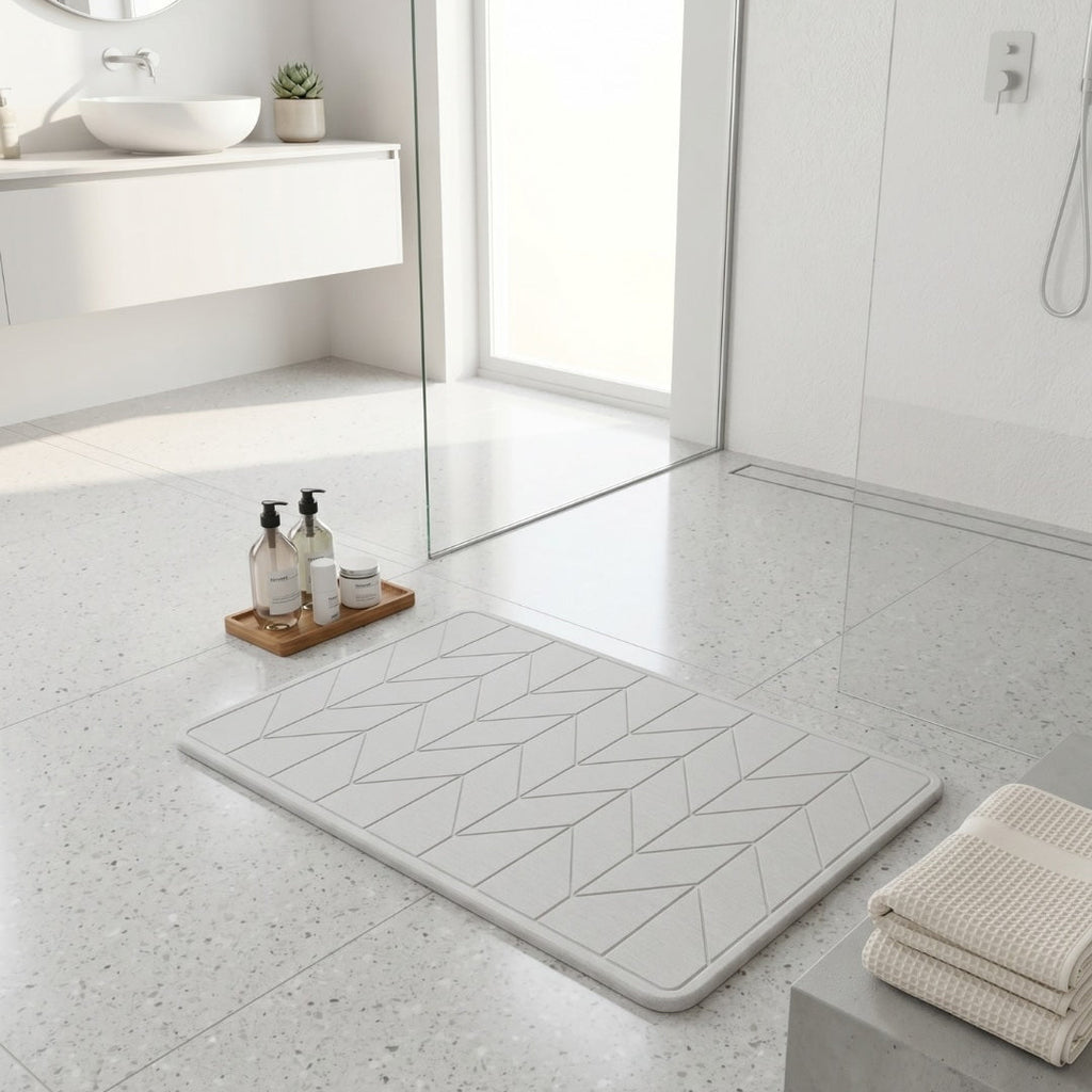 Bathroom with a textured diatomite bath mat on the floor, towels, and toiletries.